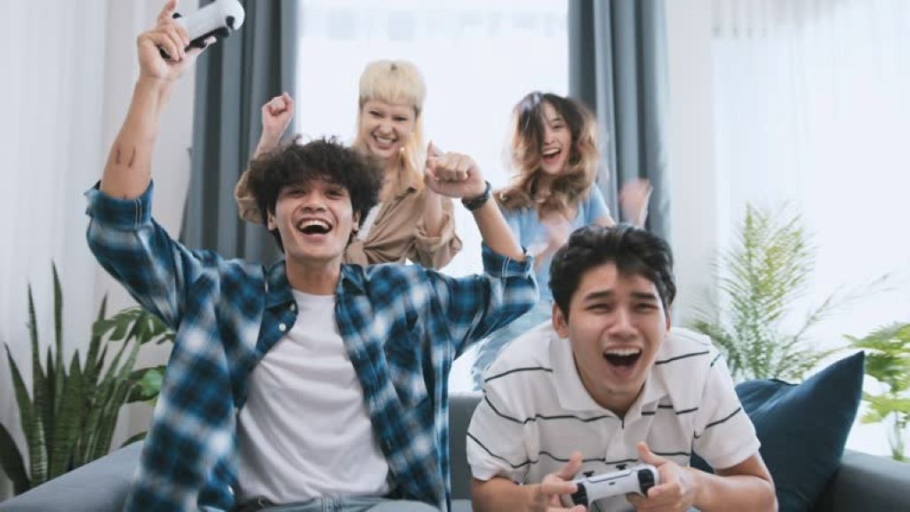 A group of diverse gamers sitting together on a couch, laughing and playing a video game with controllers in hand